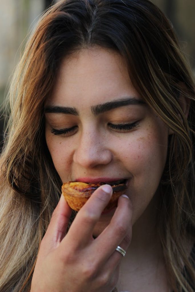 pexels photo 30826352 Close-up of a woman savoring a pastel de nata in Porto, showcasing local cuisine.