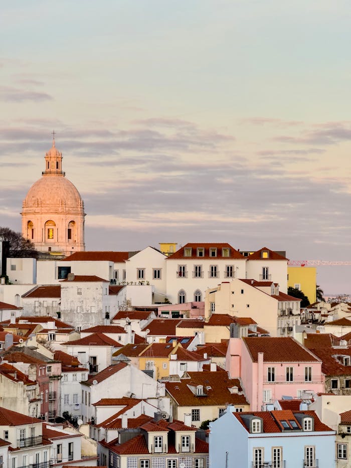 Explore the charm of Lisbon's architecture with a stunning view of classic rooftops and an iconic dome at sunset.